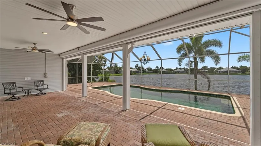 View of pool featuring a patio area, a lanai, ceiling fan, and a water view