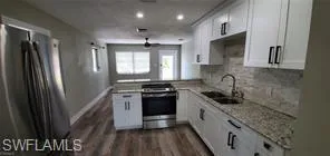 Kitchen with stainless steel appliances, white cabinets, a peninsula, dark wood-type flooring, and tasteful backsplash