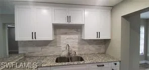 Kitchen featuring light stone countertops and white cabinets