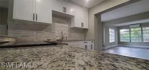 Kitchen with white cabinets and light stone counters