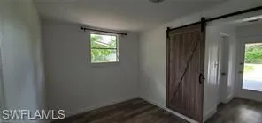 Spare room with a barn door and dark wood-style flooring