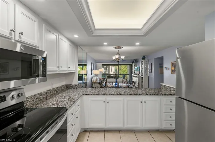 Kitchen with stainless steel appliances, a raised ceiling, and white cabinets
