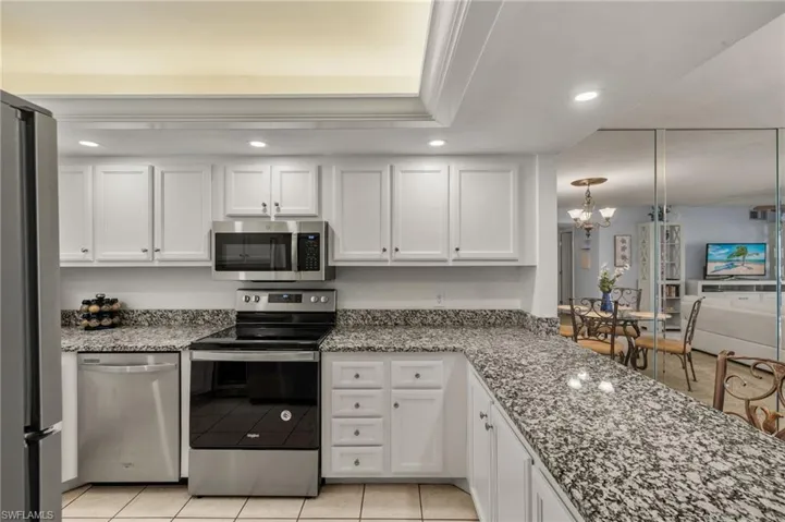 Kitchen with pendant lighting, stainless steel appliances, light tile patterned floors, and white cabinets