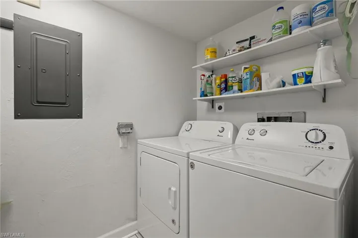 Clothes washing area featuring electric panel and independent washer and dryer