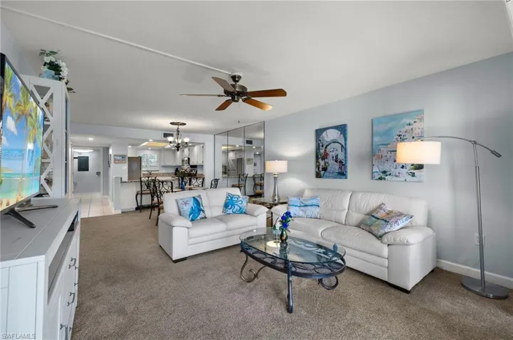 Living room featuring ceiling fan with notable chandelier and light carpet