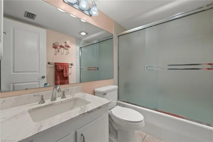 Full bathroom with tile patterned flooring, vanity, shower / bath combination with glass door, and toilet