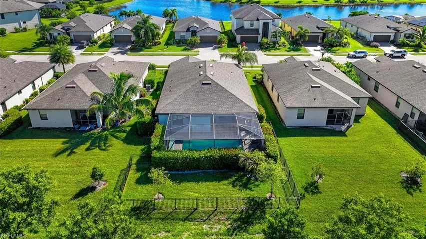 Rear Aerial View Highlighting the Screened Pool, Fenced Yard, and Well-Maintained Landscaping.