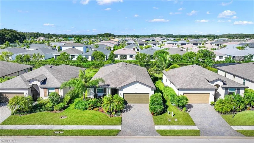 Aerial View of the Home Featuring a Screened-In Pool, Fenced Backyard, and Lush Landscaping.