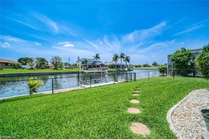 Fenced backyard featuring boat lift, a water view, and a dock