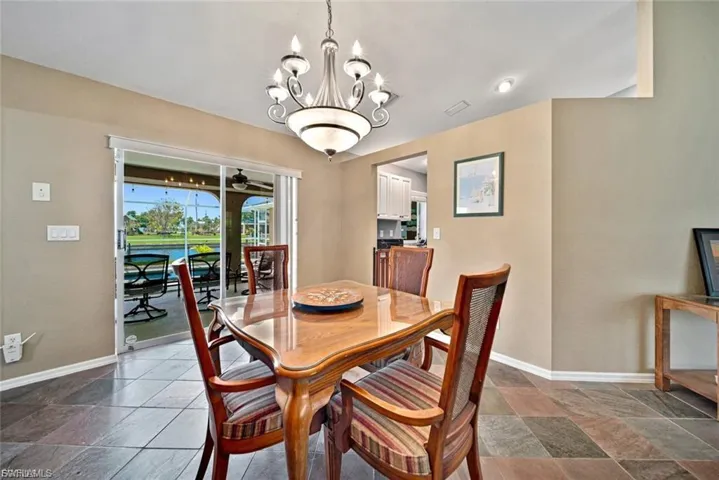 Dining room with a chandelier, stone tile flooring, and a ceiling fan