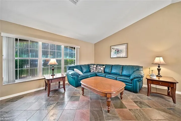 Living room featuring lofted ceiling and stone tile flooring