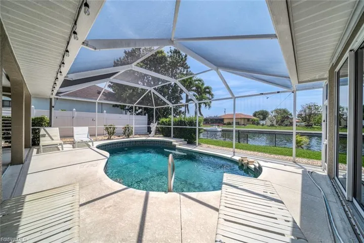 View of swimming pool with a patio, a sunroom, glass enclosure, and a water view