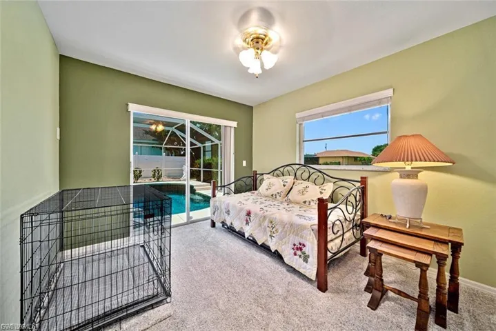 Carpeted bedroom featuring access to outside, a sunroom, and a ceiling fan