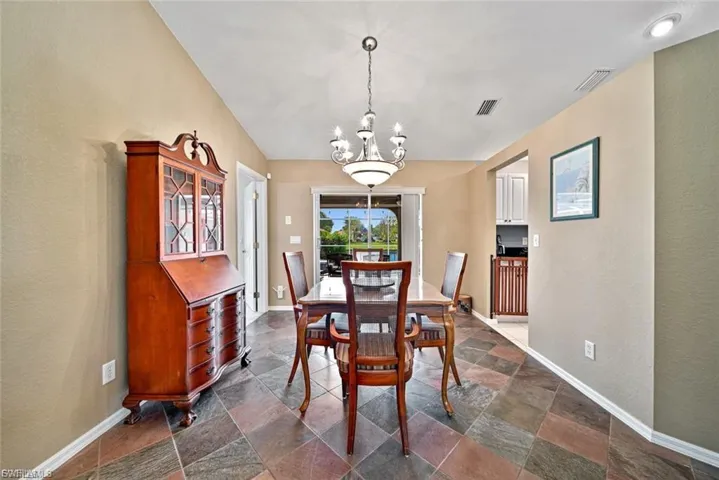 Dining area with a textured wall, a chandelier, and stone tile floors