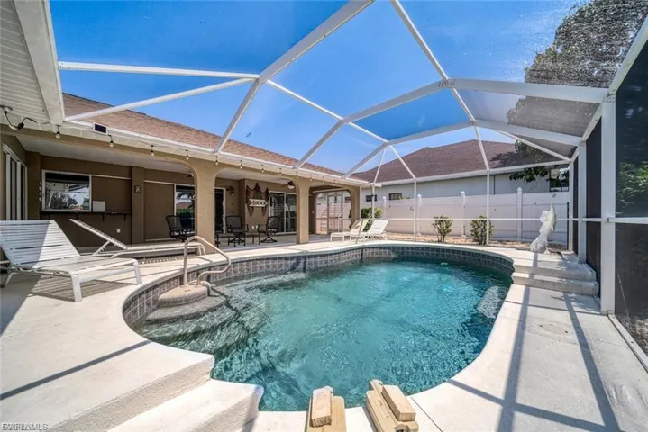 View of pool with a sunroom, glass enclosure, and a patio