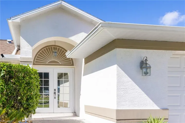 View of exterior entry with stucco siding and french doors