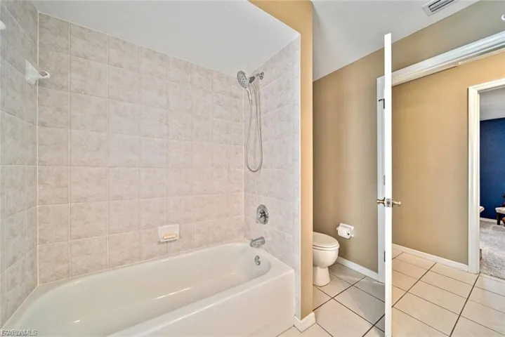 Full bath with washtub / shower combination and tile patterned flooring