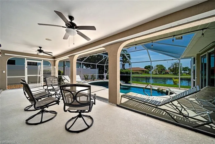 View of patio / terrace with a sunroom, ceiling fan, a water view, a lanai, and an outdoor pool