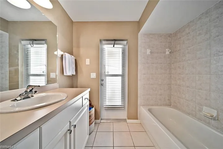 Full bathroom with light tile patterned floors, vanity, and washtub / shower combination