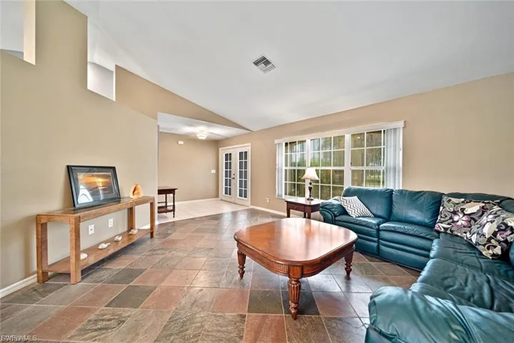 Living area featuring vaulted ceiling and stone tile floors