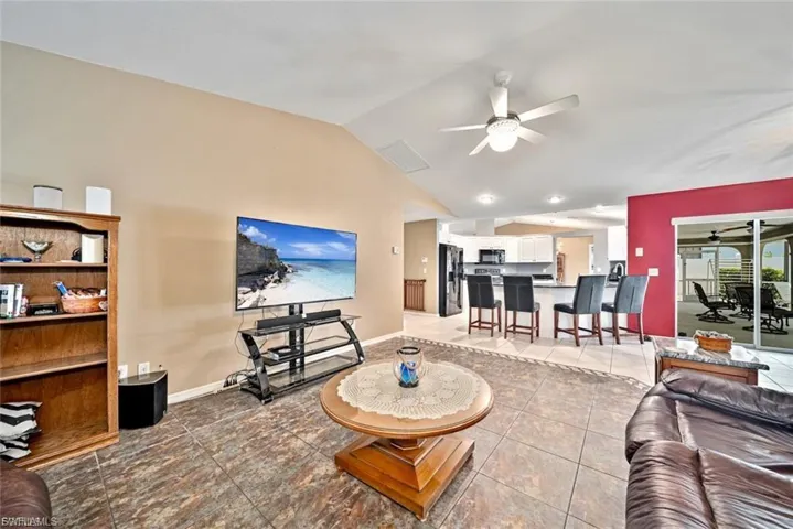 Tiled living room featuring vaulted ceiling and a ceiling fan