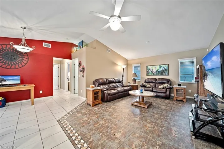 Living room with lofted ceiling, ceiling fan, and tile patterned floors