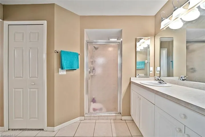 Full bath featuring vanity, a closet, light tile patterned flooring, and a shower stall