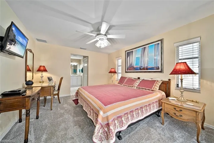 Bedroom with a ceiling fan, carpet floors, ensuite bath, and an office area