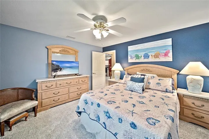 Bedroom featuring light colored carpet, a ceiling fan, and a textured wall