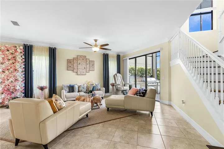 Living room featuring a ceiling fan, ornamental molding, and light tile patterned flooring
