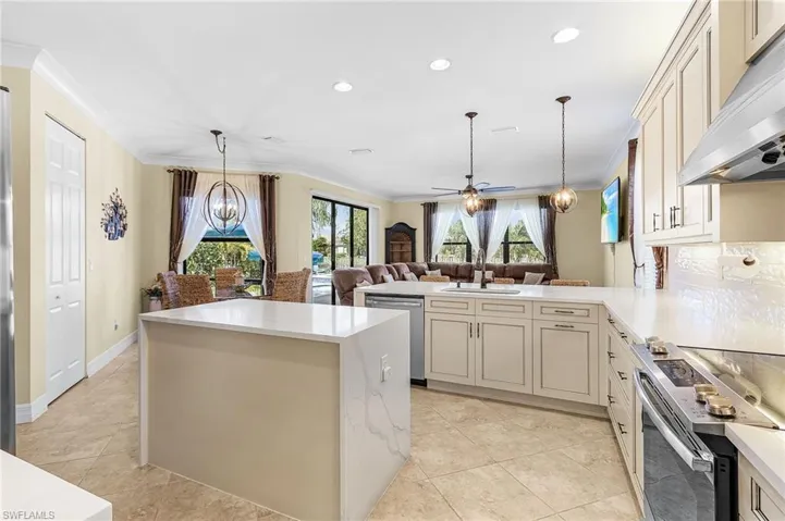 Kitchen featuring hanging lights, stainless steel appliances, a peninsula, open floor plan, and ceiling fan