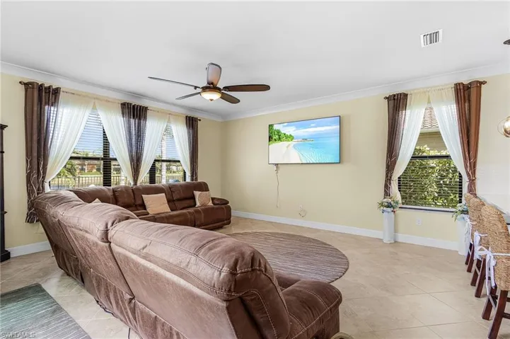 Living area with ceiling fan, crown molding, and light tile patterned flooring
