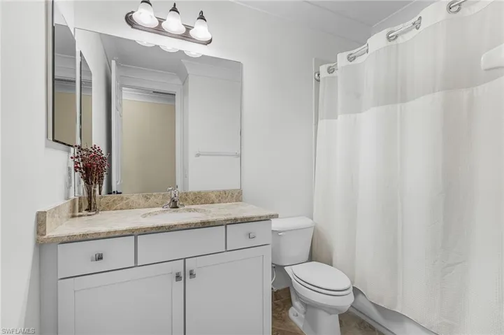 Bathroom featuring shower / tub combo, vanity, crown molding, and dark tile patterned floors