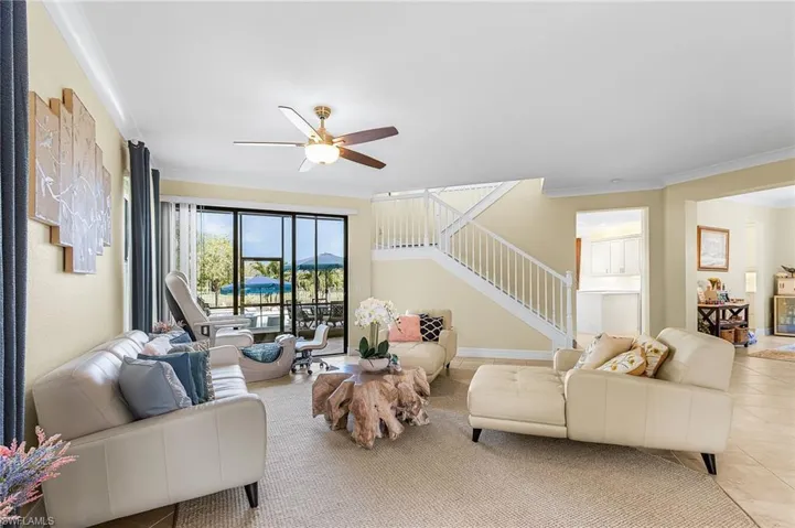 Living room with crown molding, ceiling fan, and tile patterned flooring