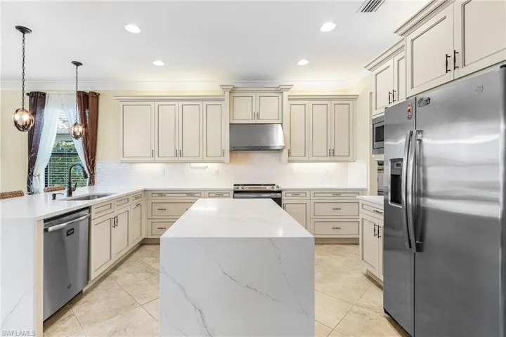 Kitchen with stainless steel appliances, a peninsula, light stone counters, decorative backsplash, and crown molding