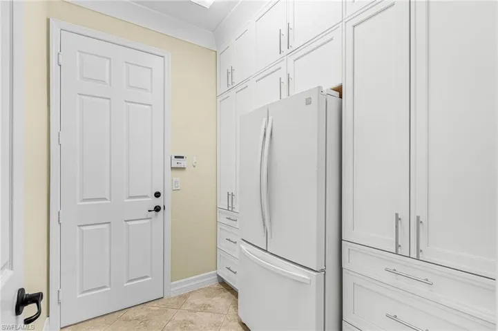 Laundry area featuring light tile patterned flooring and baseboards
