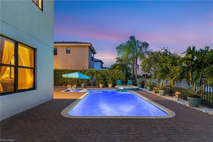 Pool at dusk featuring a fenced backyard, a patio, and a pool with connected hot tub