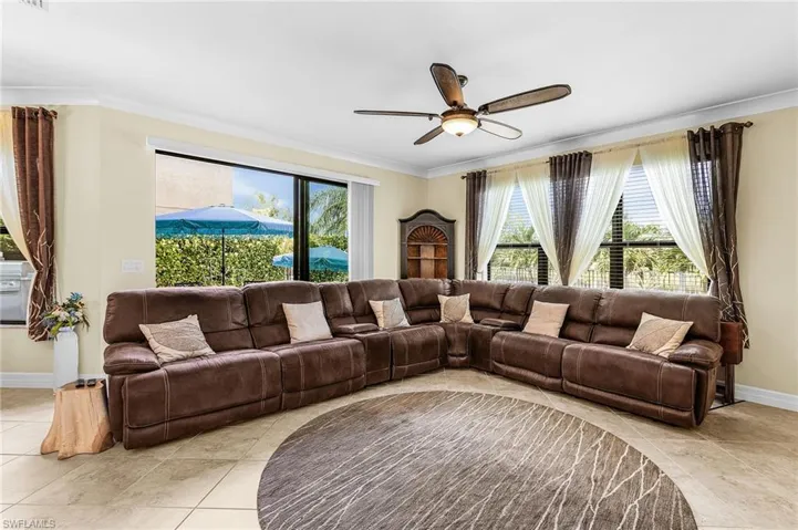 Living area featuring crown molding, ceiling fan, and light tile patterned flooring