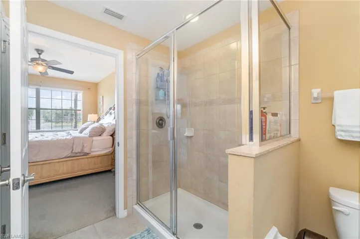 Full bathroom with connected bathroom, a stall shower, ceiling fan, and toilet