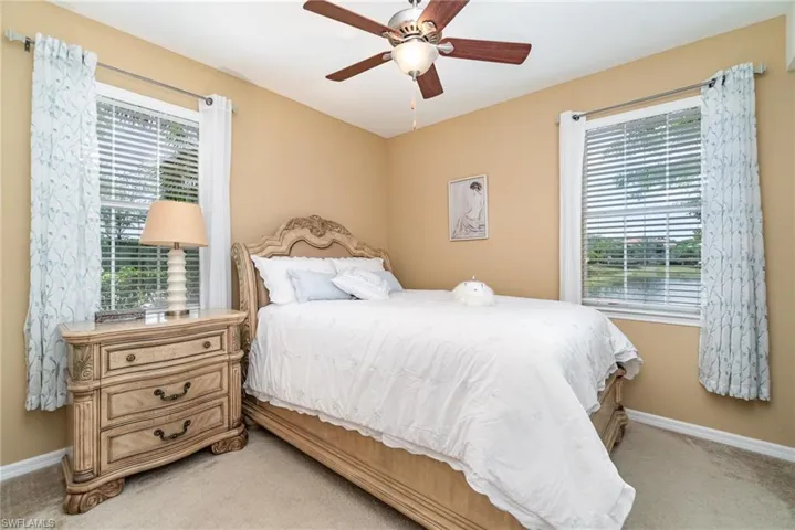 Bedroom with light carpet, baseboards, and a ceiling fan