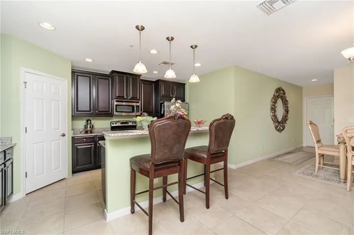 Kitchen with appliances with stainless steel finishes, light tile patterned floors, a kitchen bar, recessed lighting, and baseboards