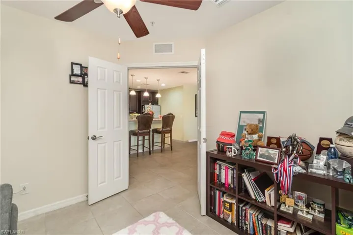 Living area with a ceiling fan, light tile patterned flooring, and baseboards