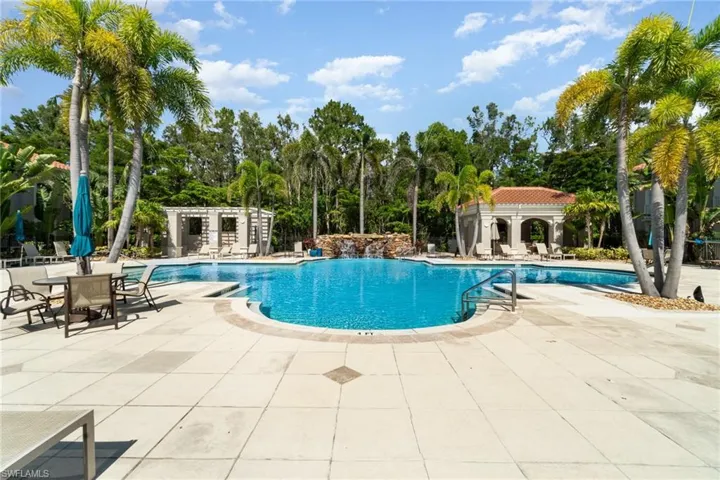 Community pool with a patio area and view of scattered trees