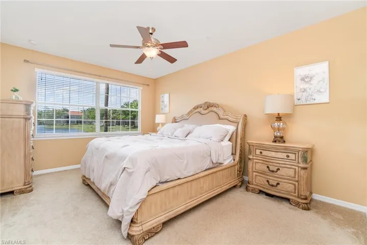 Bedroom with light carpet, baseboards, and a ceiling fan