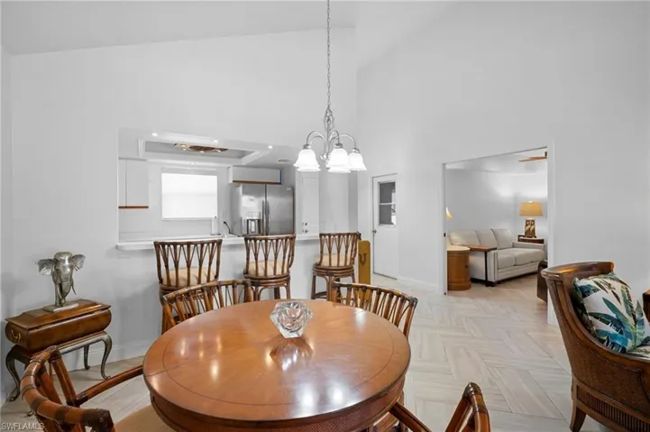 Dining space with suspended lighting, vaulted ceiling, and parquet flooring