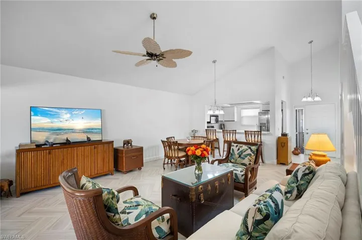 Living room with suspended lighting, ceiling fan, parquet flooring, and lofted ceiling