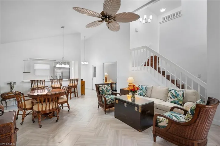 Living area with hanging lights, a ceiling fan, parquet floors, and vaulted ceiling