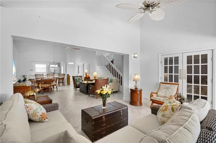 Living room with ceiling fan, a high ceiling, and parquet flooring