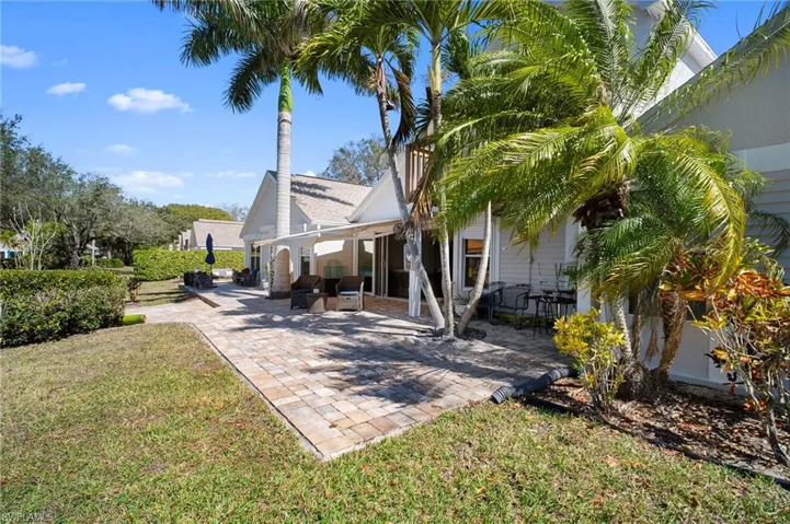 Back of property featuring a patio, a yard, and a shingled roof