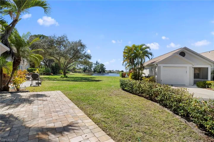 View of grassy yard featuring a water view, a patio area, and an attached garage